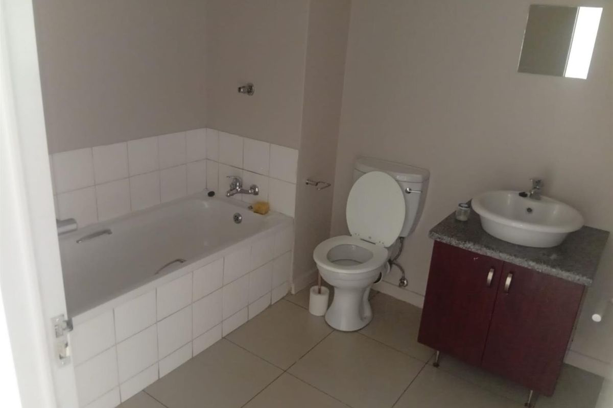 A functional bathroom featuring a tiled bathtub, a standard toilet, and a vanity cabinet with a basin and granite countertop.