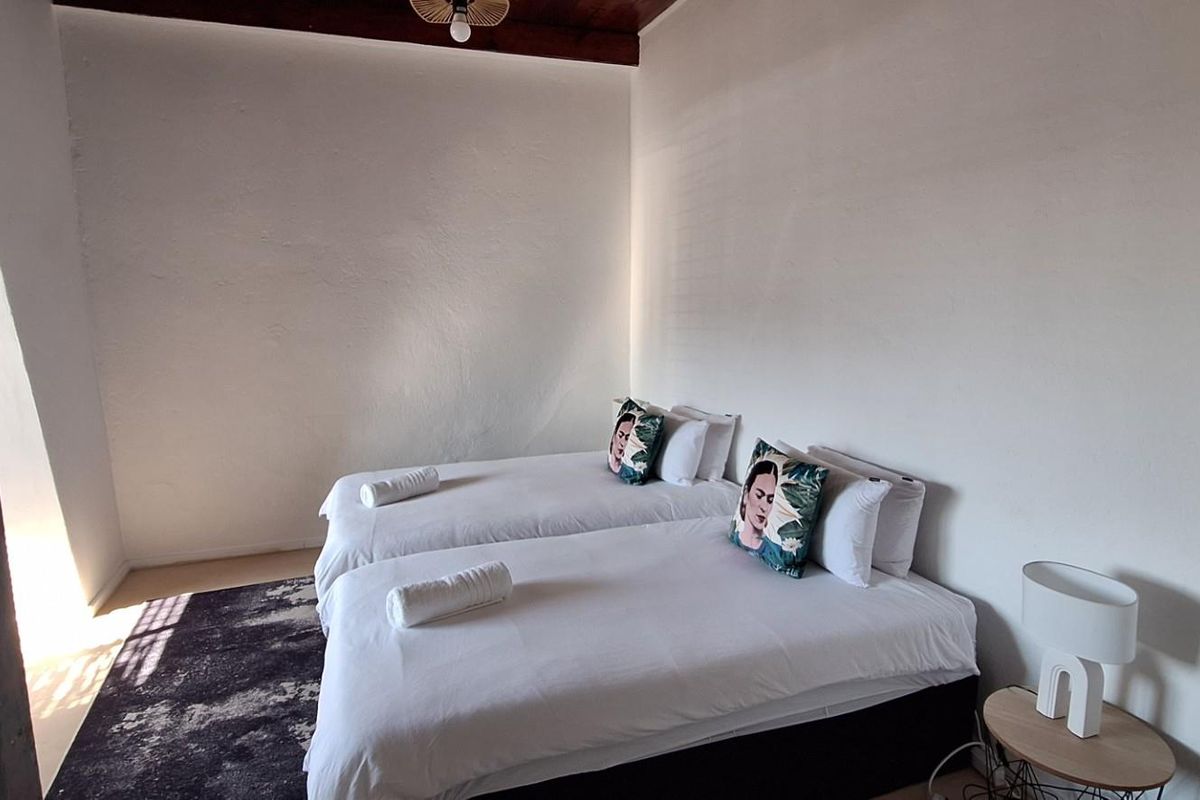 A bedroom featuring white walls and a dark wood ceiling, providing a simple and functional sleeping space.