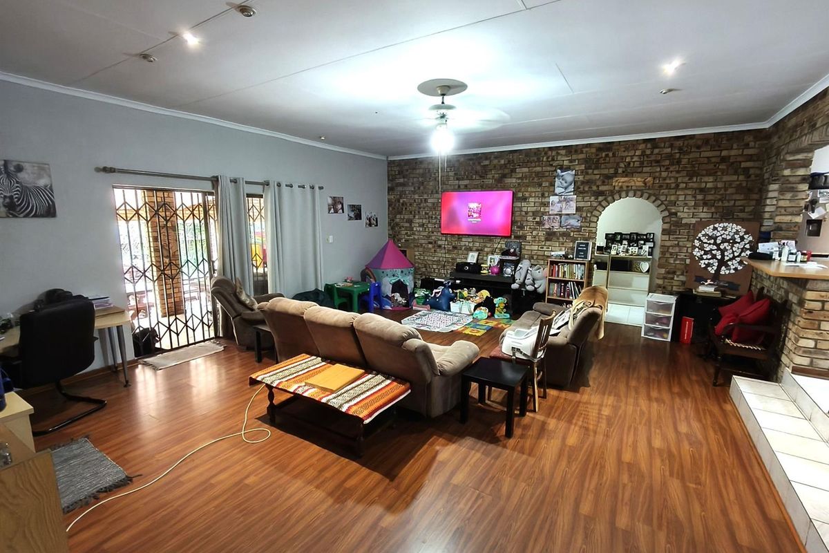 Spacious living room featuring a prominent exposed brick feature wall, laminate wood flooring, and direct access to an outdoor patio area.
