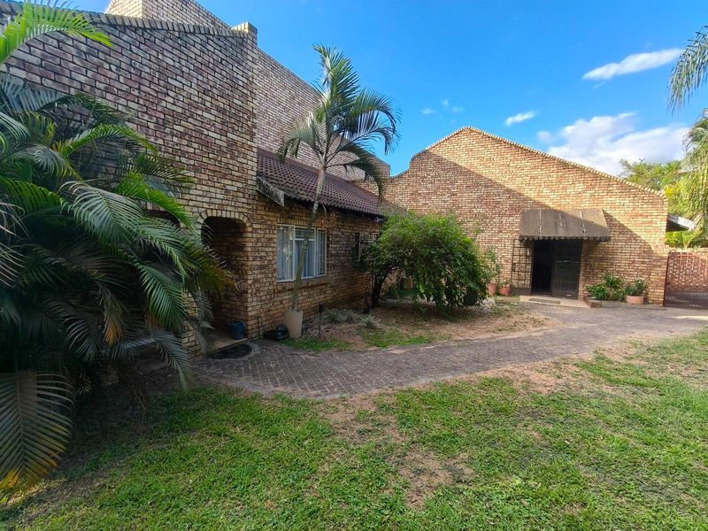Exterior view of a face-brick house featuring a paved walkway, established garden, and multiple entrance points.