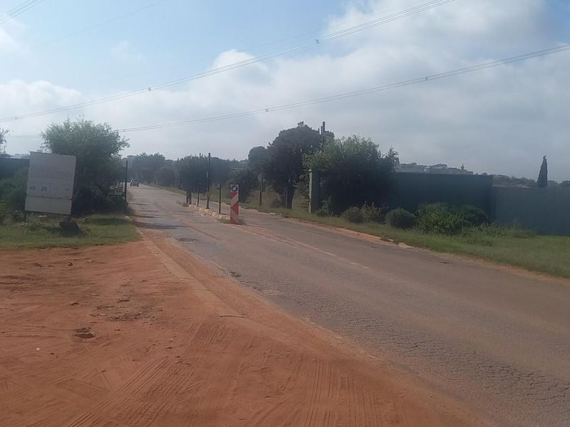 A view of the street frontage and surrounding area of the vacant residential land, featuring paved road access and overhead power lines.