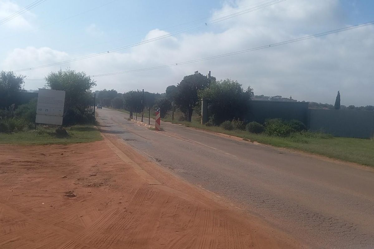 A view of the street frontage and surrounding area of the vacant residential land, featuring paved road access and overhead power lines.