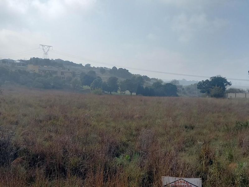 A view of a vacant residential plot featuring natural grass coverage and surrounding landscape.