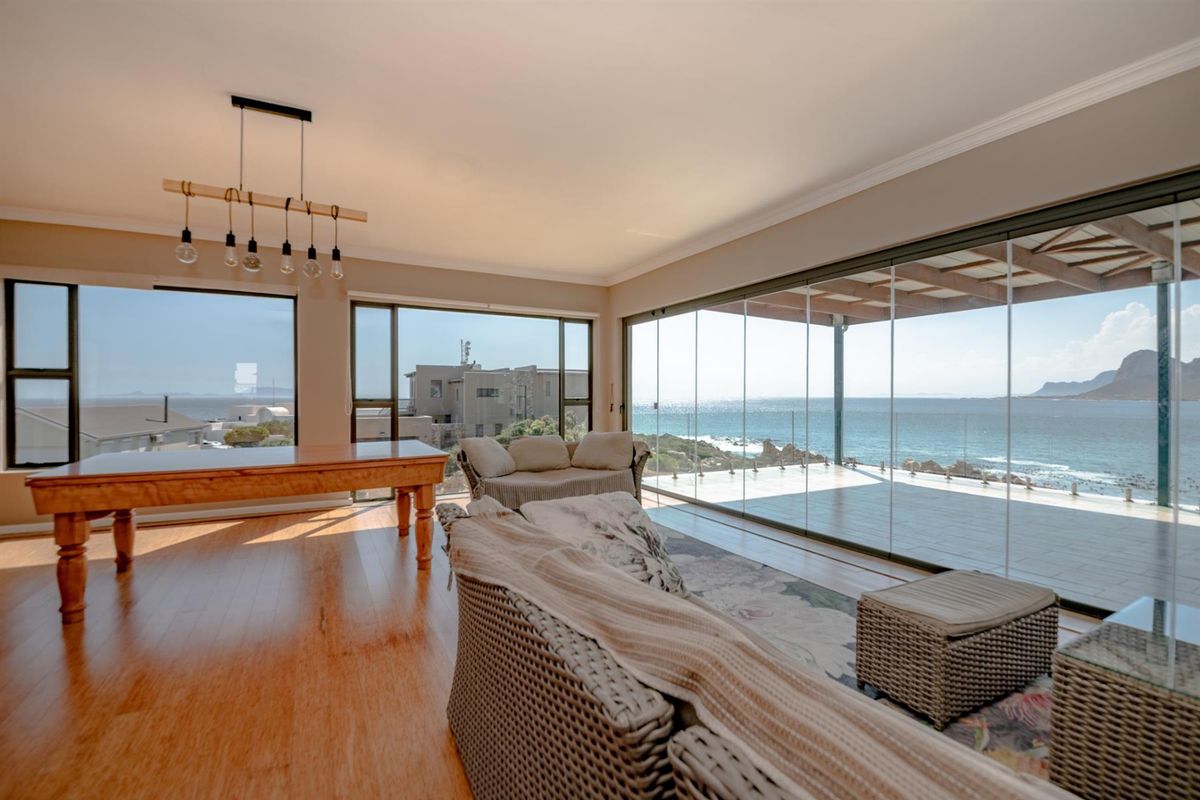 Spacious living area featuring large glass sliding doors that open onto a patio with panoramic ocean views.