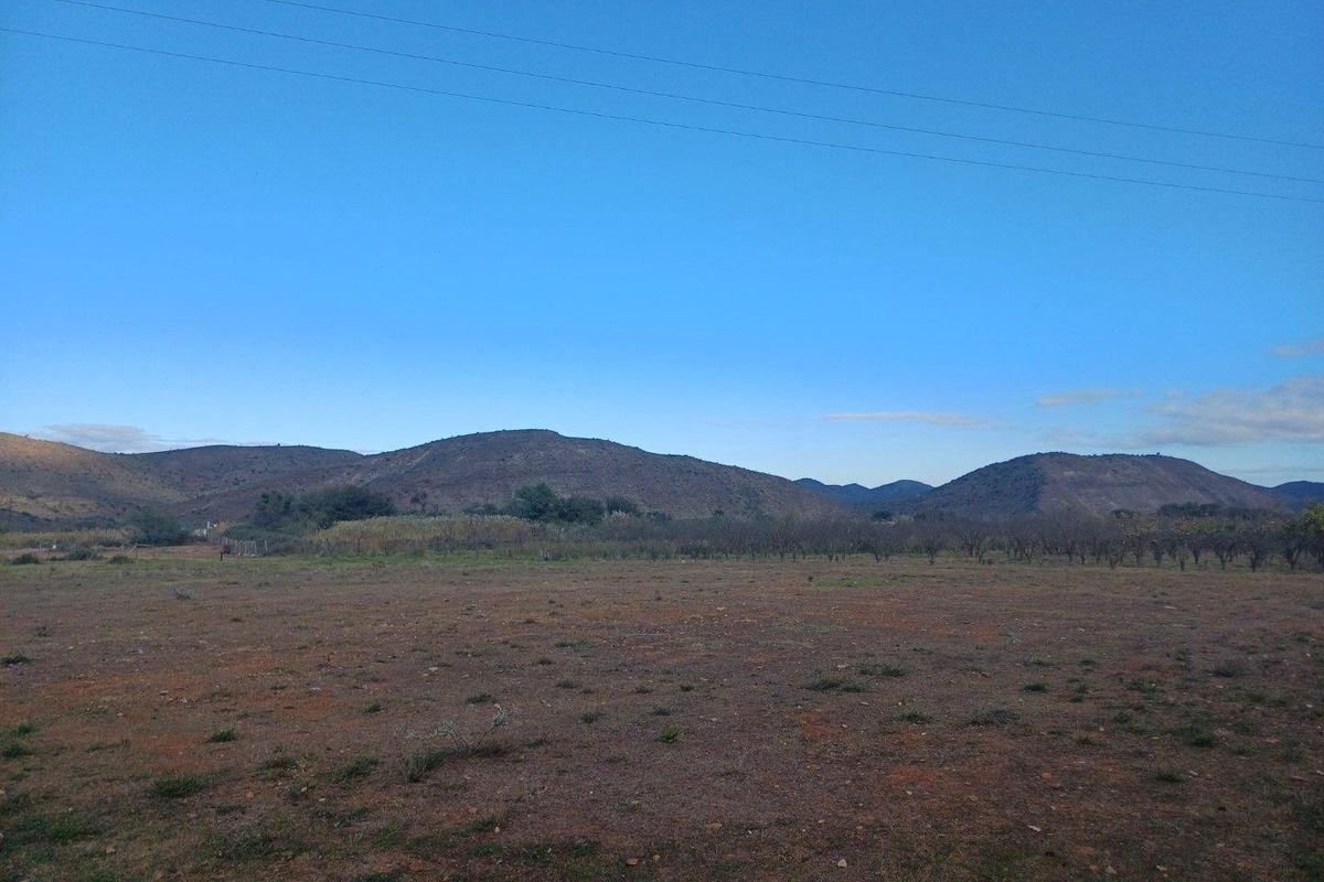 A wide-angle view of a vacant residential plot featuring natural terrain and scenic mountain views in the background.