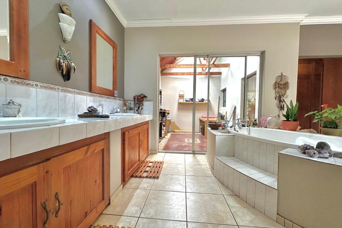 Spacious bathroom featuring a double vanity with wooden cabinetry, tiled countertops, and a sunken bathtub, with direct access to an outdoor area.