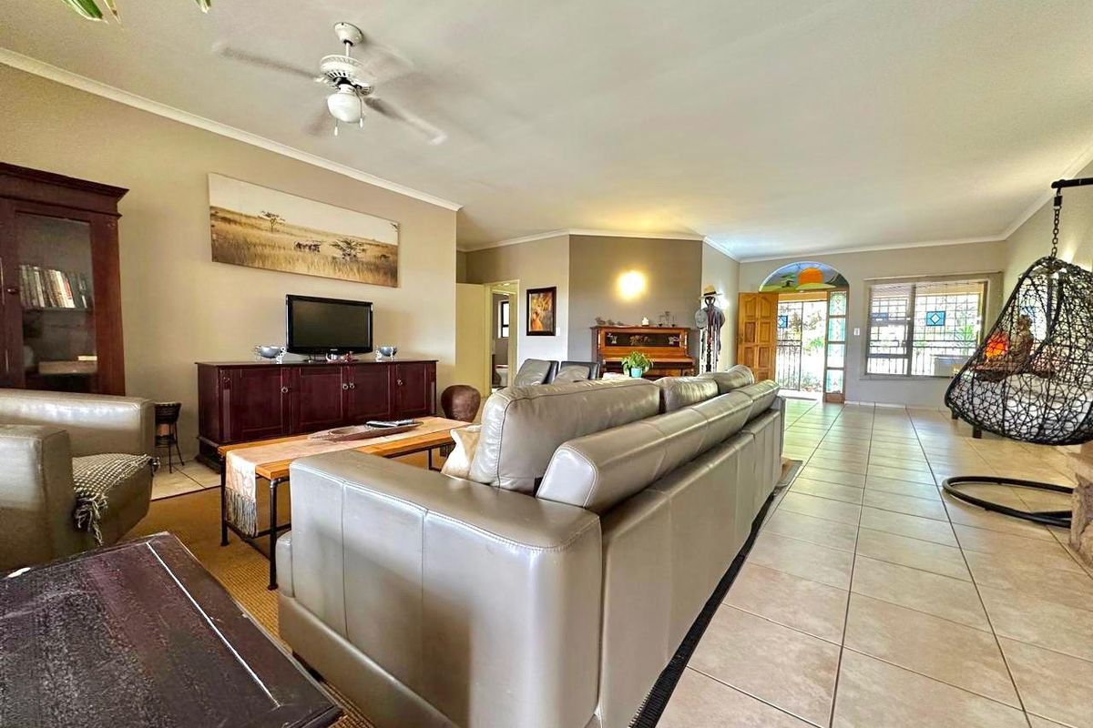 Spacious living room featuring ceramic floor tiles, a ceiling fan, and an arched entryway leading to the exterior.