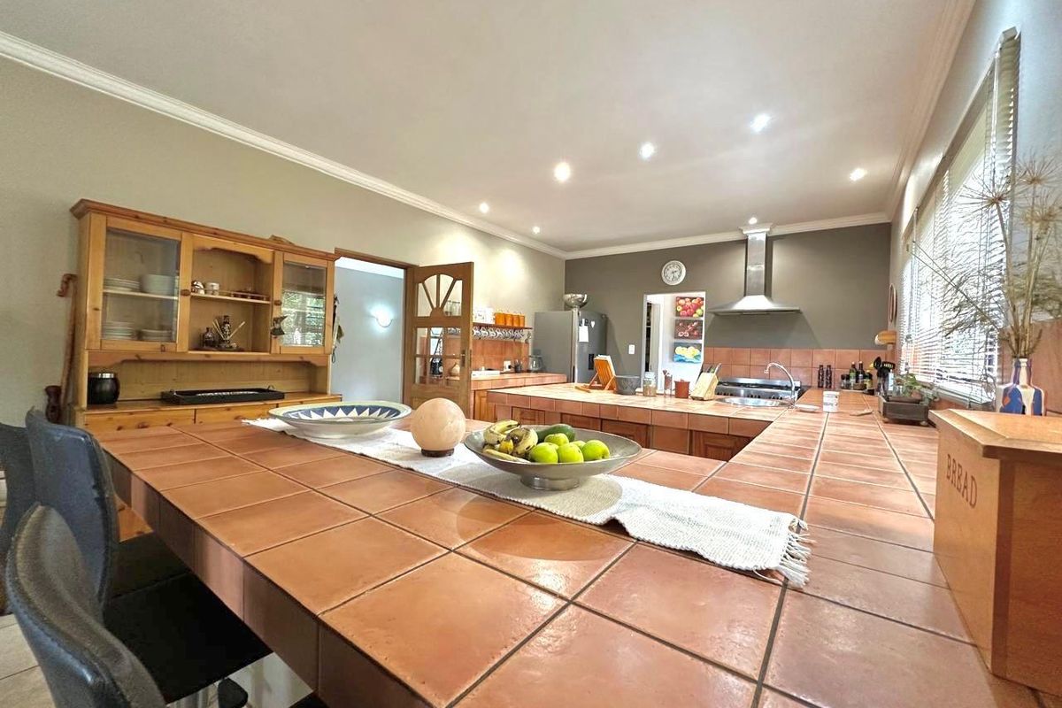 Spacious kitchen featuring a large tiled island, built-in cabinetry, and stainless steel extractor fan, offering a functional layout with ample counter space.