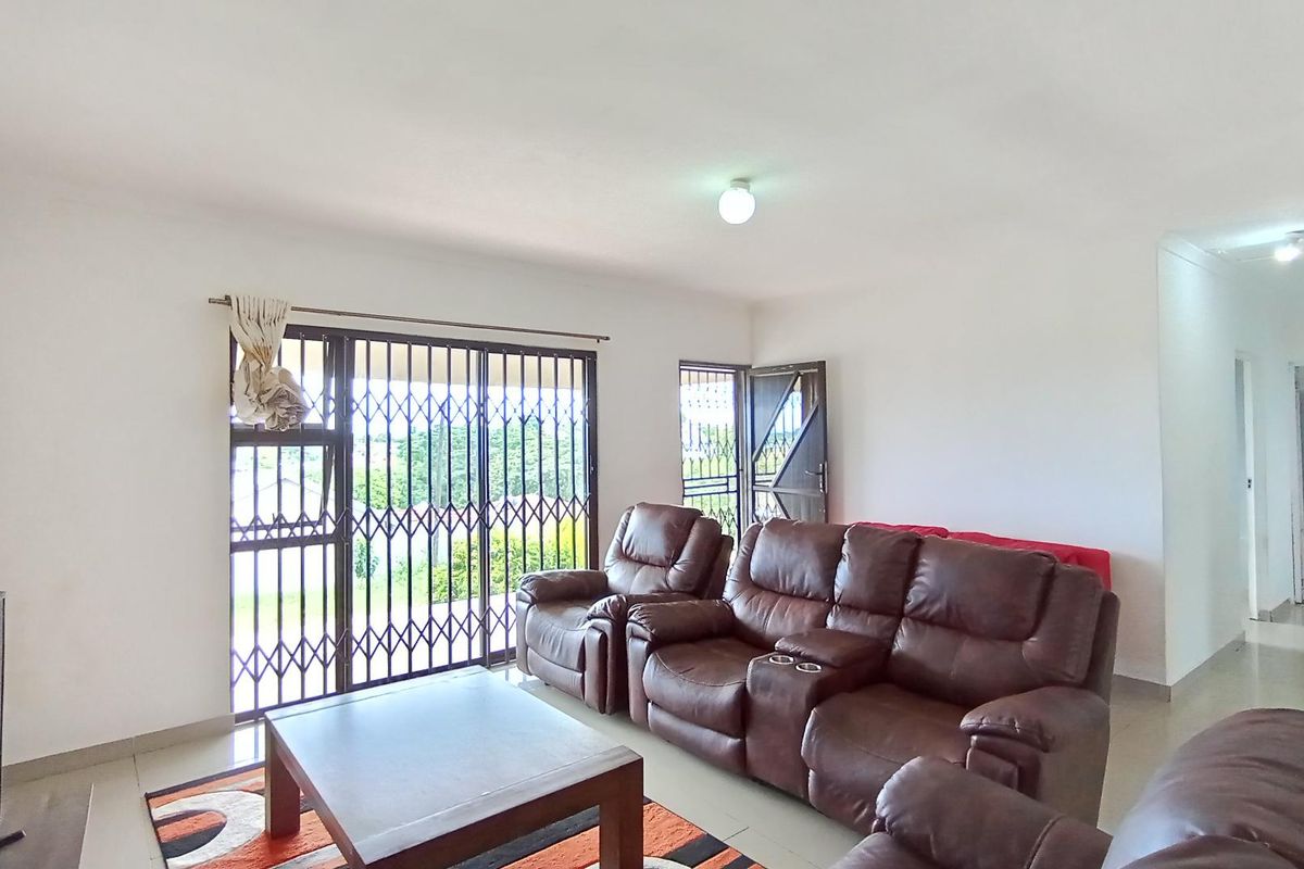 A bright living room featuring tiled flooring and a sliding glass door with integrated security gate, providing access to the outdoor area.