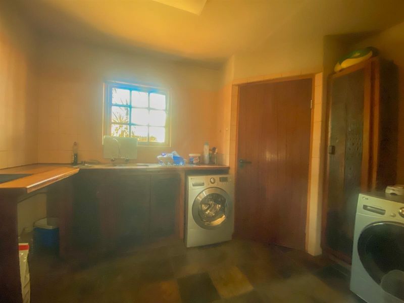 A functional laundry room featuring built-in cabinetry, a sink, and tiled finishes, providing a practical space for household utility tasks.