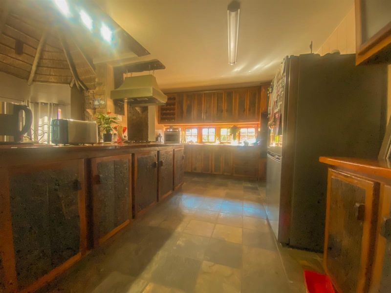 A rustic kitchen featuring wooden cabinetry, stone tile flooring, and a built-in extractor fan, offering a traditional aesthetic with potential for modernization.