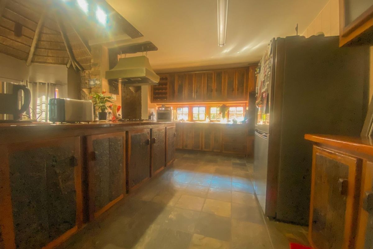A rustic kitchen featuring wooden cabinetry, stone tile flooring, and a built-in extractor fan, offering a traditional aesthetic with potential for modernization.