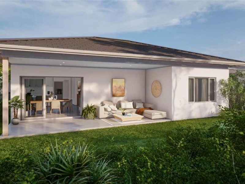 A rear view of a modern residential property featuring a covered patio area, sliding glass doors, and a well-maintained garden.