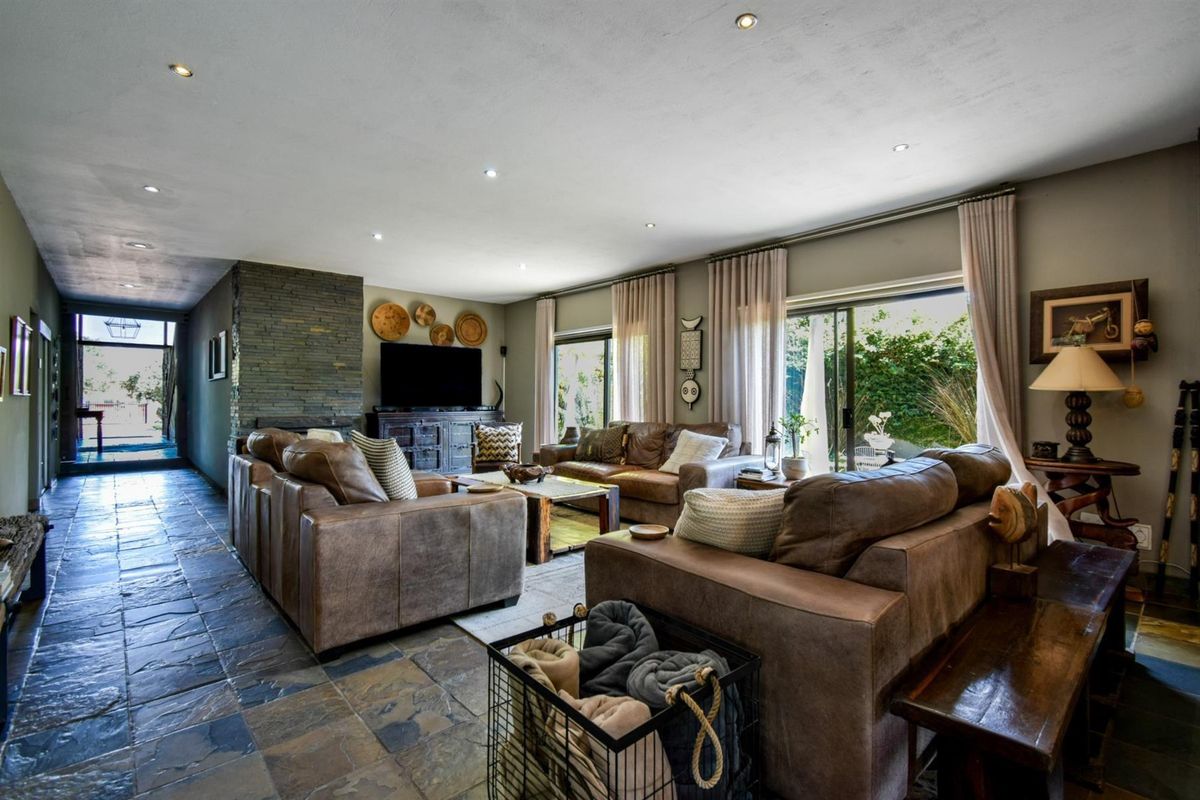 Spacious living room featuring natural stone flooring, a stone-clad fireplace feature wall, and large sliding glass doors providing access to the garden.