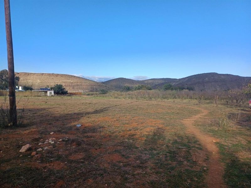 A wide-angle view of the vacant residential land featuring natural terrain, surrounding hills, and a utility pole on the property boundary.