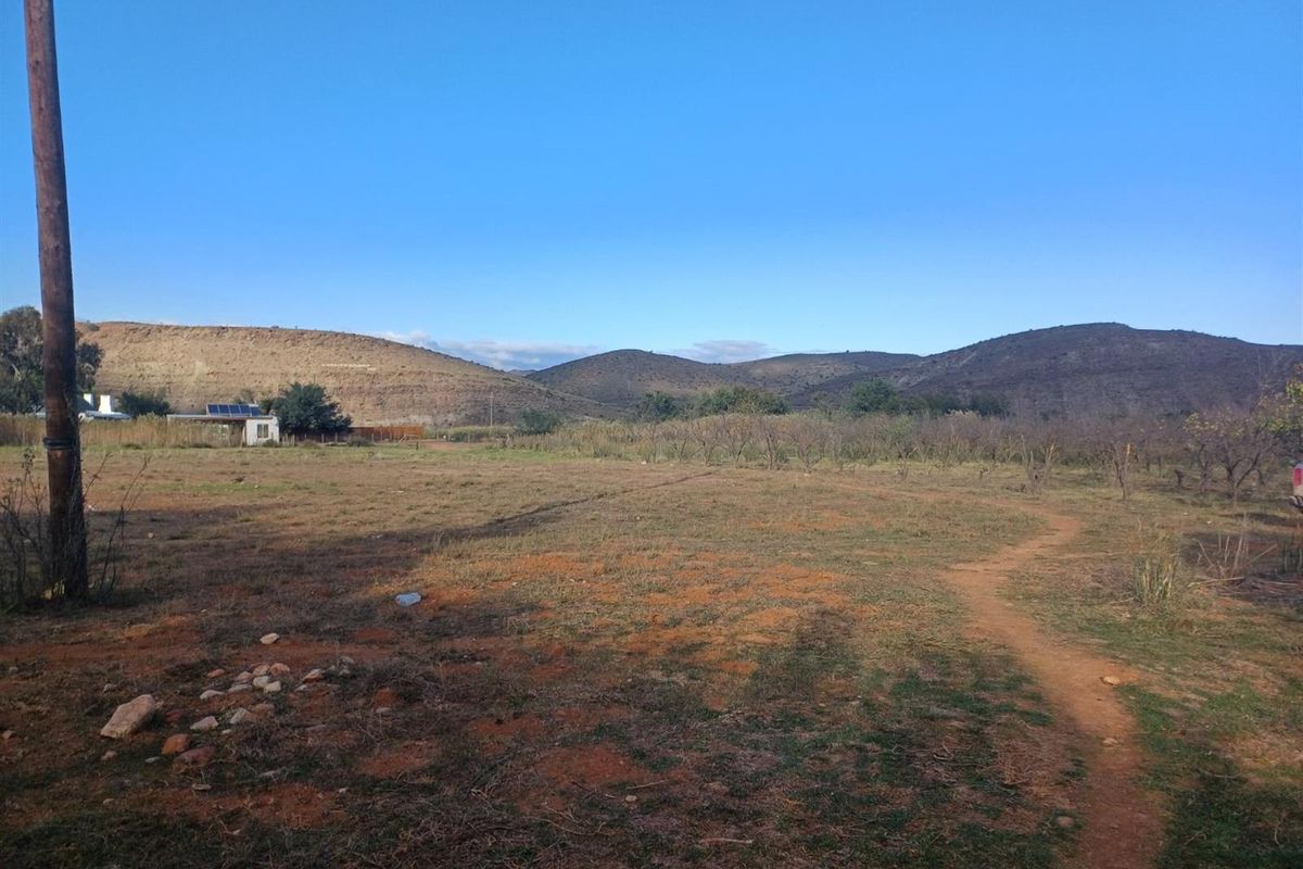 A wide-angle view of the vacant residential land featuring natural terrain, surrounding hills, and a utility pole on the property boundary.