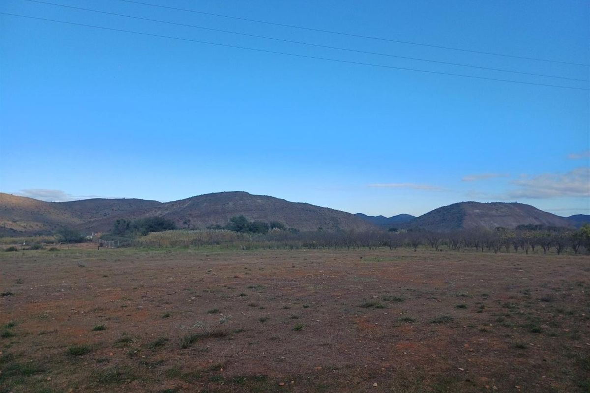 A wide-angle view of a vacant residential plot featuring natural terrain and scenic mountain vistas in the background.