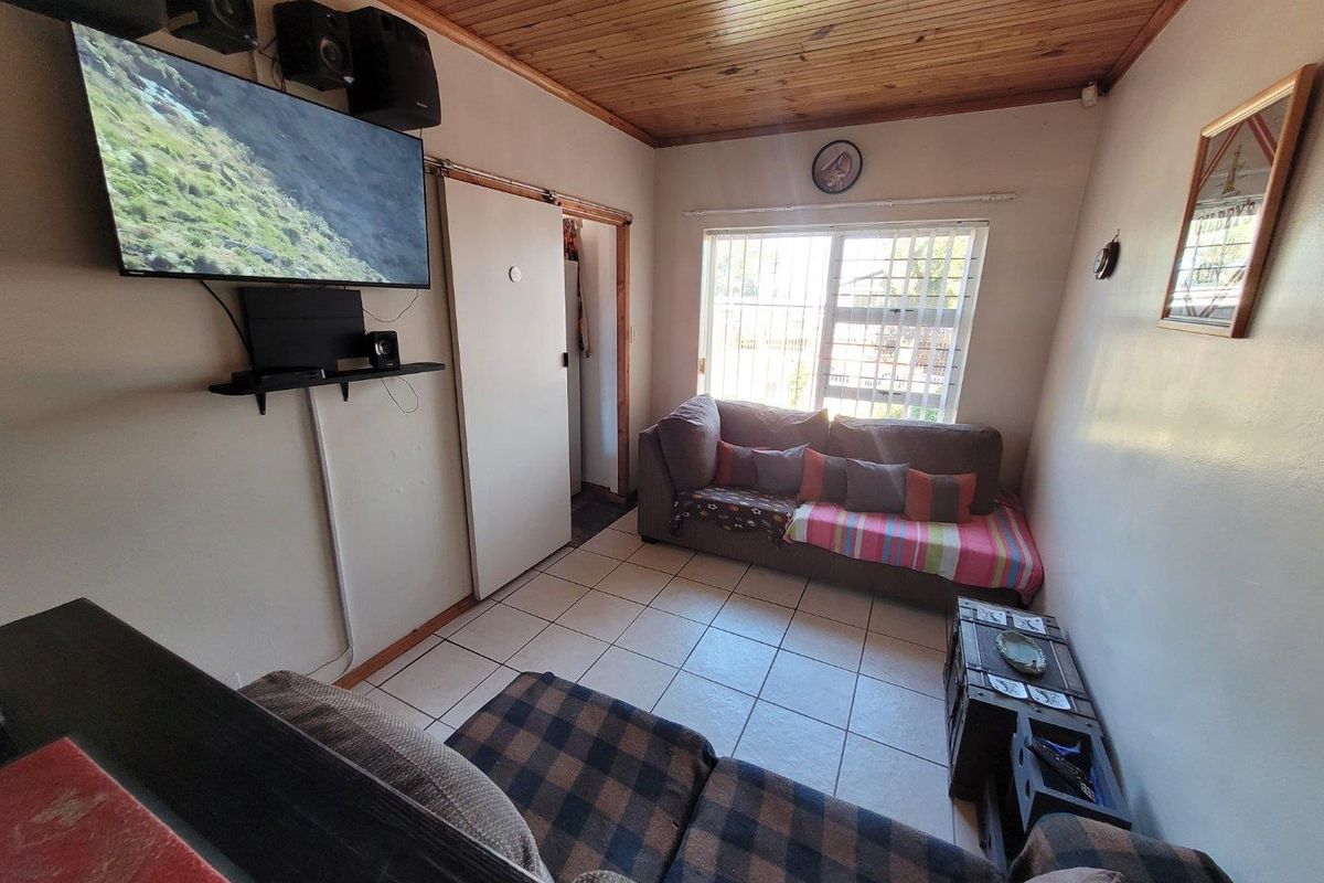 A compact living room featuring ceramic floor tiles and a timber tongue and groove ceiling, providing a functional space with natural light.