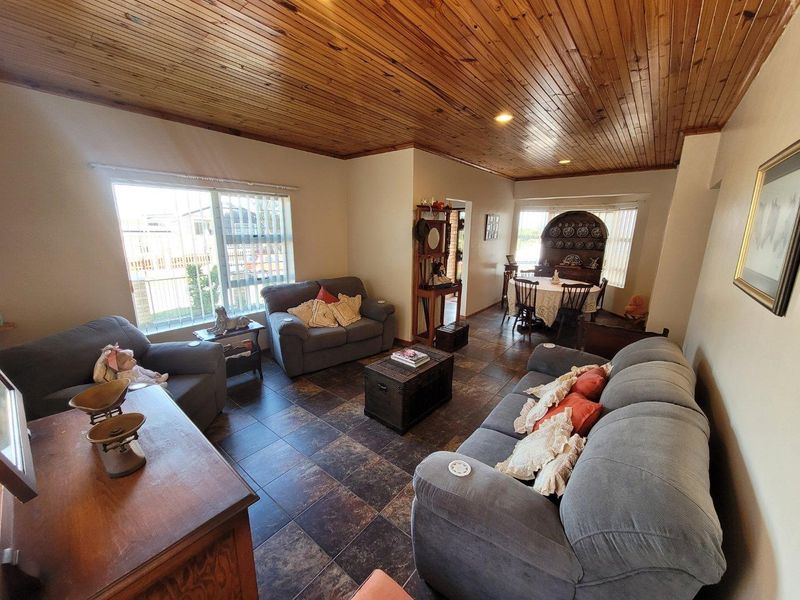 Open plan living and dining area featuring dark tiled flooring and a warm timber tongue and groove ceiling with recessed lighting.