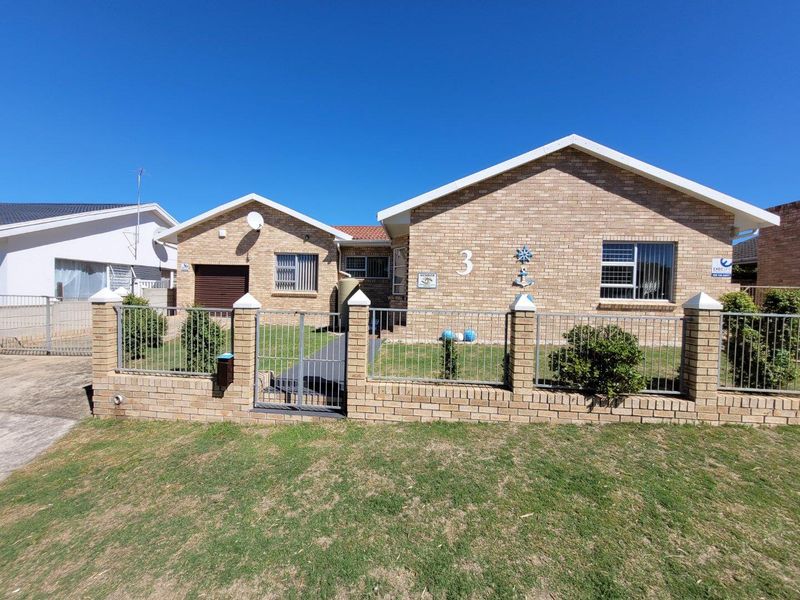 Front view of a single-story brick house featuring a secure gated entrance, a front garden, and an integrated garage.