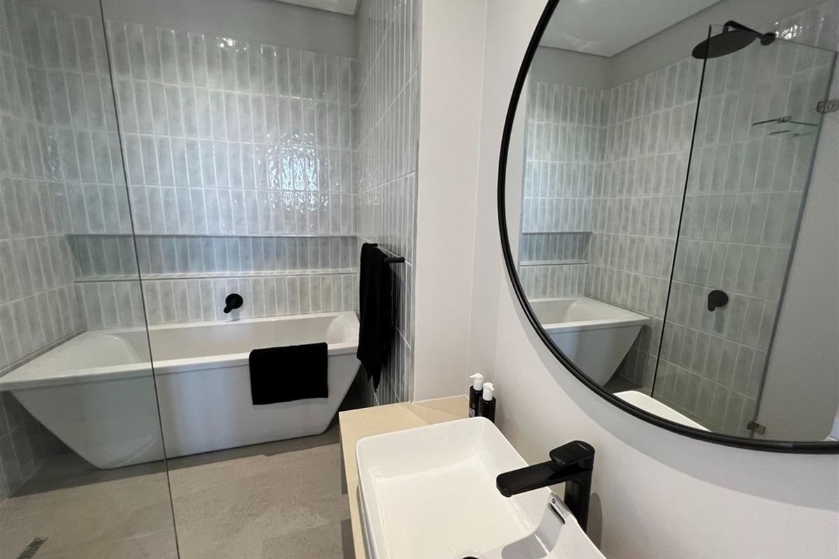 Modern bathroom featuring a sleek freestanding bathtub, walk-in shower with glass screen, vessel sink, and contemporary matte black fixtures.