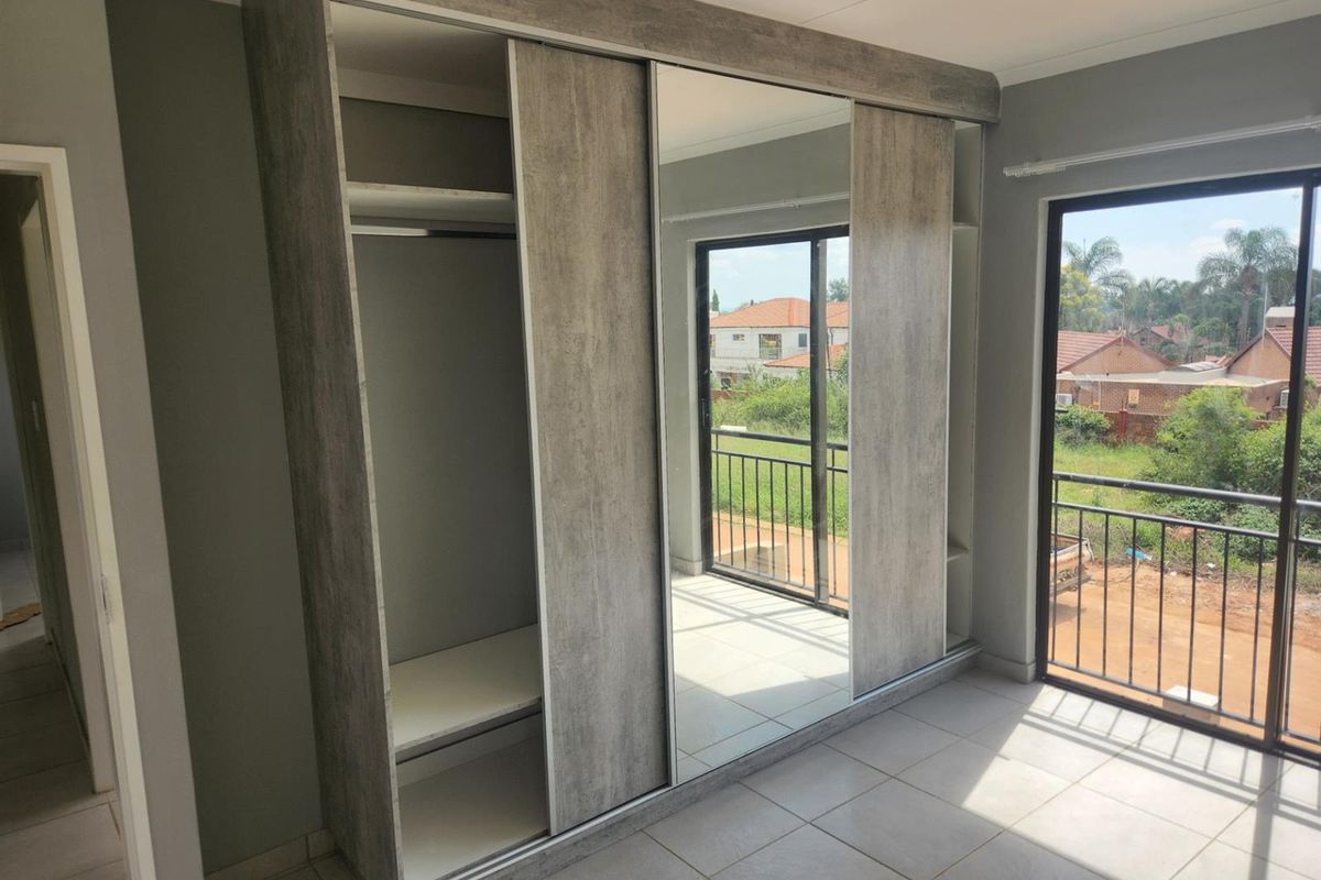 A bedroom featuring built-in sliding door wardrobes with a mirrored panel and direct access to a private balcony.