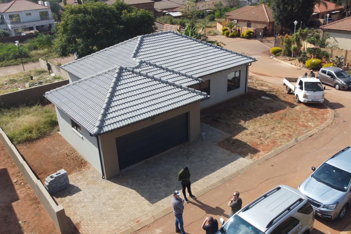 Aerial view of a modern single-story residential house featuring a tiled roof, paved driveway, and an integrated garage.