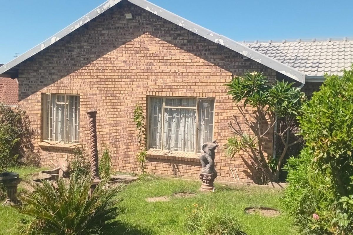 A view of the rear brick facade of the house, featuring a garden area and established landscaping.