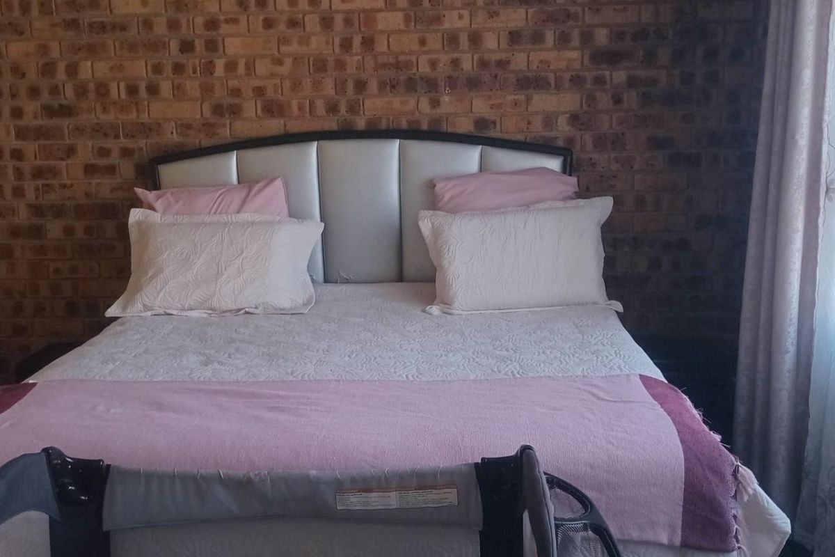 A bedroom featuring a prominent exposed brick feature wall and built-in wardrobe storage.