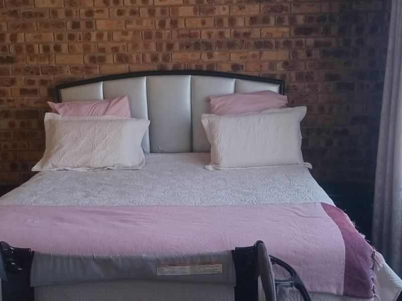 A bedroom featuring a prominent exposed brick feature wall and built-in wardrobe storage.