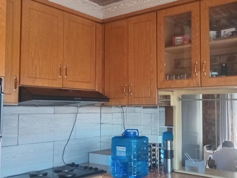 A kitchen featuring wood-finish cabinetry, a built-in oven, a hob, and an extractor fan with a tiled backsplash.