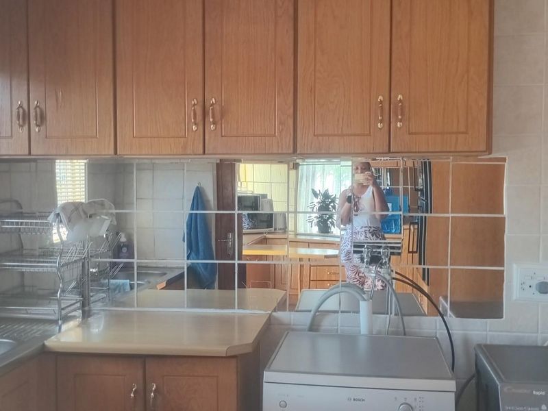 A functional laundry or scullery area featuring wooden cabinetry, tiled splashbacks, and dedicated plumbing connections for laundry appliances.