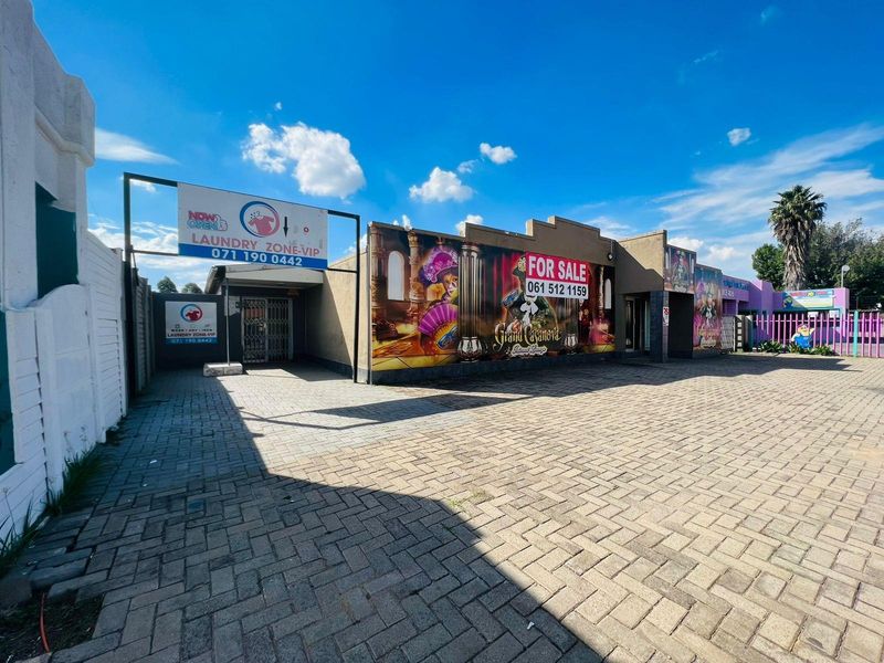 Commercial property exterior featuring paved frontage, signage for a laundry business, and prominent branding for a lounge venue.