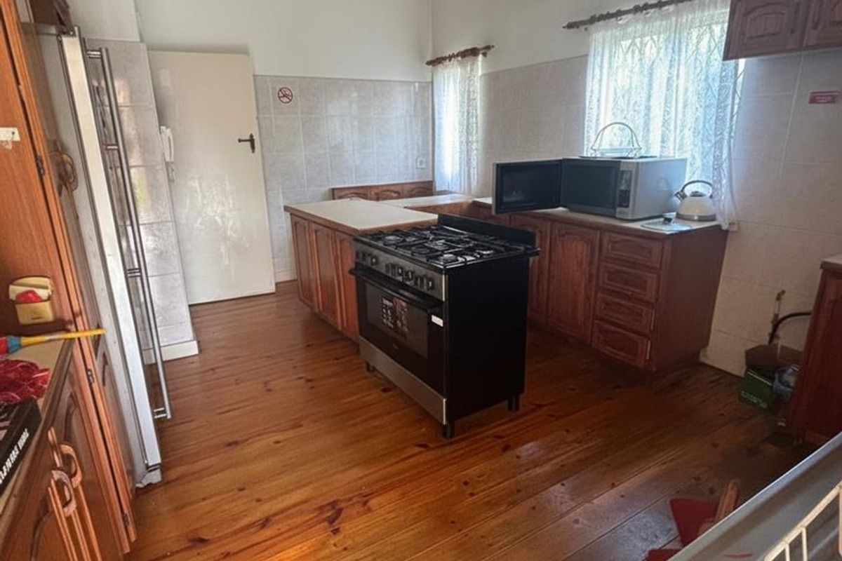 A spacious kitchen featuring timber cabinetry, a freestanding gas stove, and original timber flooring, offering a functional layout with potential for modernization.
