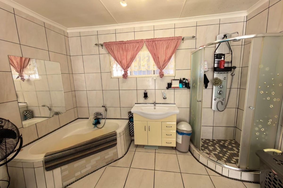 A functional bathroom featuring a corner bathtub, a separate glass-enclosed shower, and a vanity basin with tiled walls and flooring.