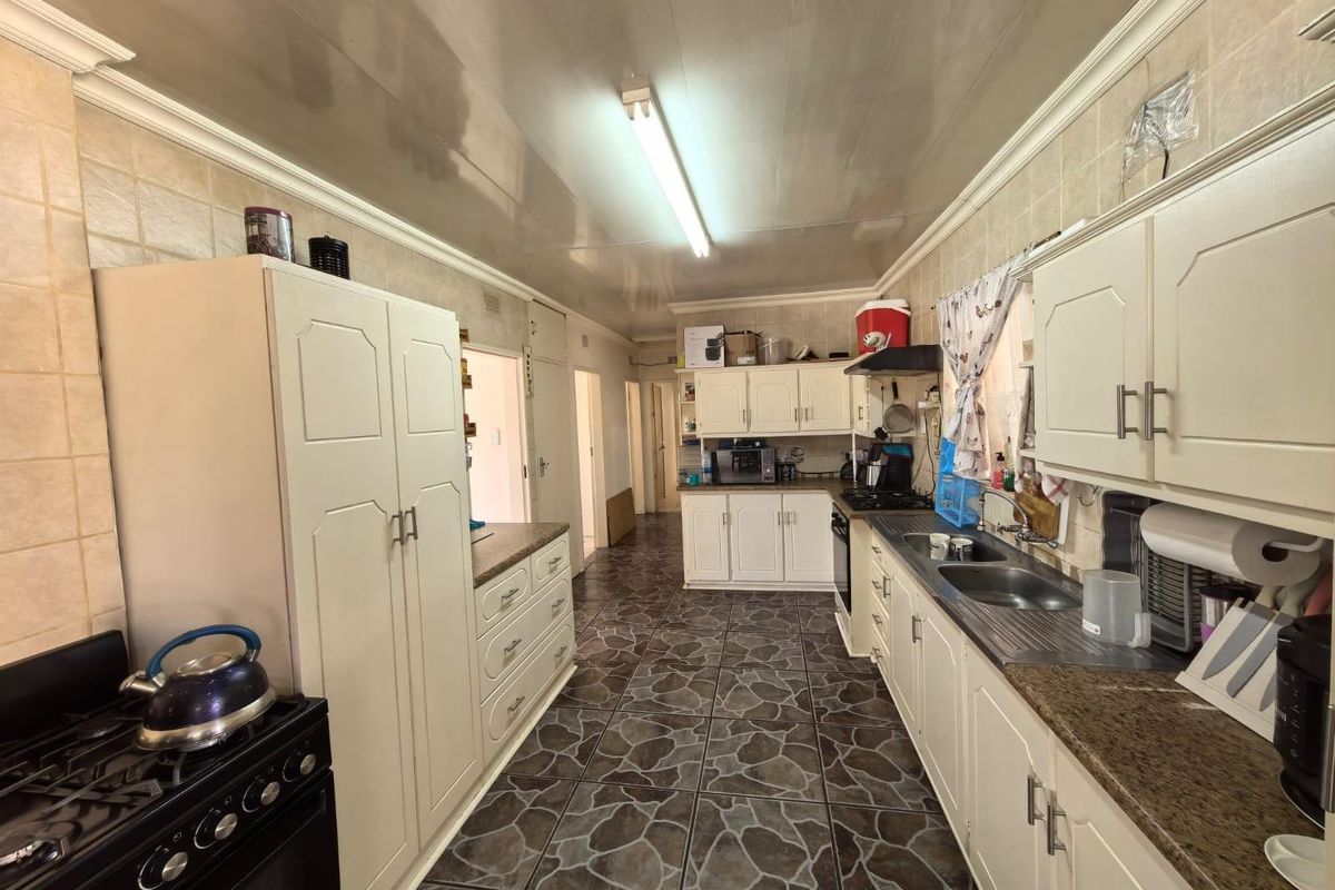 A functional galley-style kitchen featuring ample cabinetry, double basin sink, and tiled flooring, offering a practical layout for daily meal preparation.