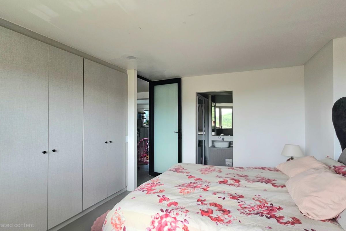 A well-lit bedroom featuring extensive built-in floor-to-ceiling cabinetry and an adjoining en-suite bathroom with a modern vanity.