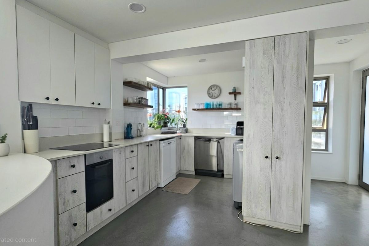Modern kitchen featuring light wood-grain cabinetry, integrated oven and hob, subway tile backsplash, and polished concrete flooring.