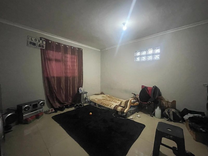 A bedroom featuring tiled flooring, a small glass block window, and coved ceiling detailing, offering a blank canvas for potential renovation and interior design updates.