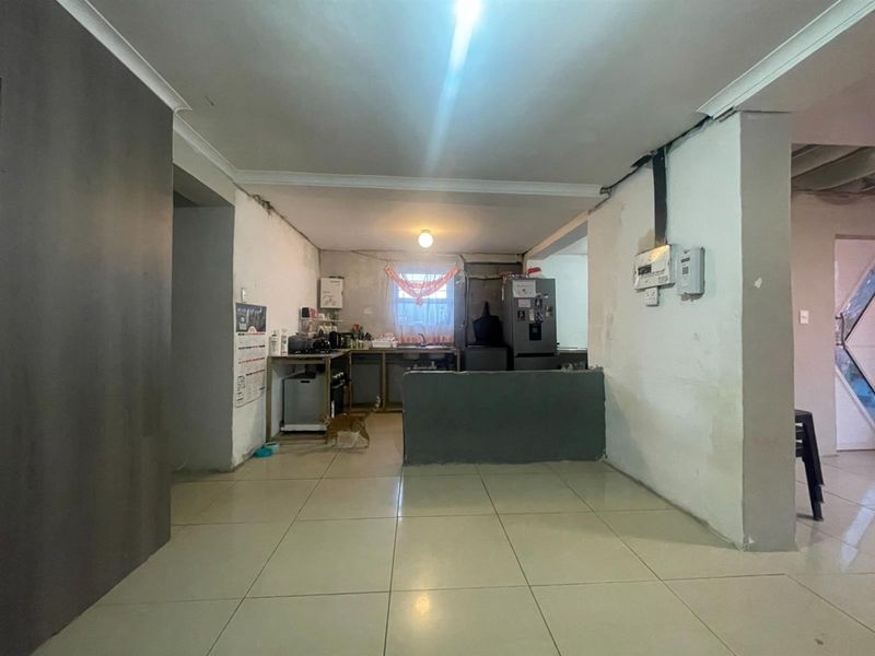 A basic kitchen area featuring tiled flooring and a functional sink, currently requiring significant cosmetic updates and wall repairs to improve the overall finish.