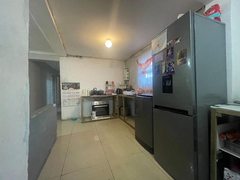 A functional kitchen area featuring tiled flooring, a built-in oven, and a sink, currently requiring cosmetic updates and cabinetry installation to improve utility and aesthetics.