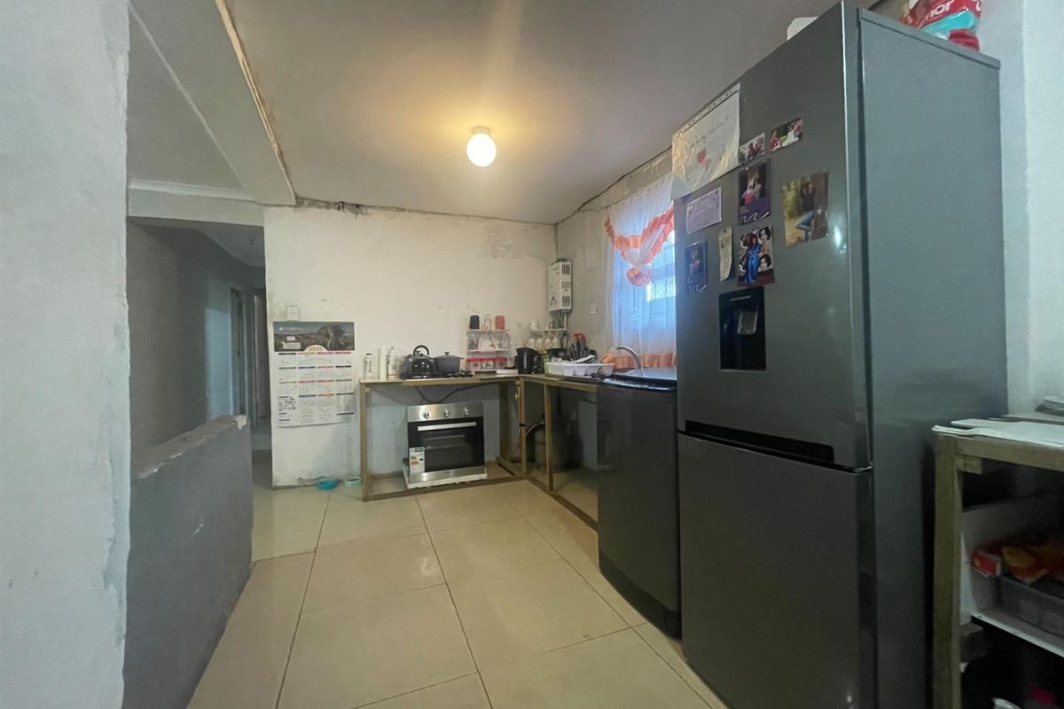A functional kitchen area featuring tiled flooring, a built-in oven, and a sink, currently requiring cosmetic updates and cabinetry installation to improve utility and aesthetics.