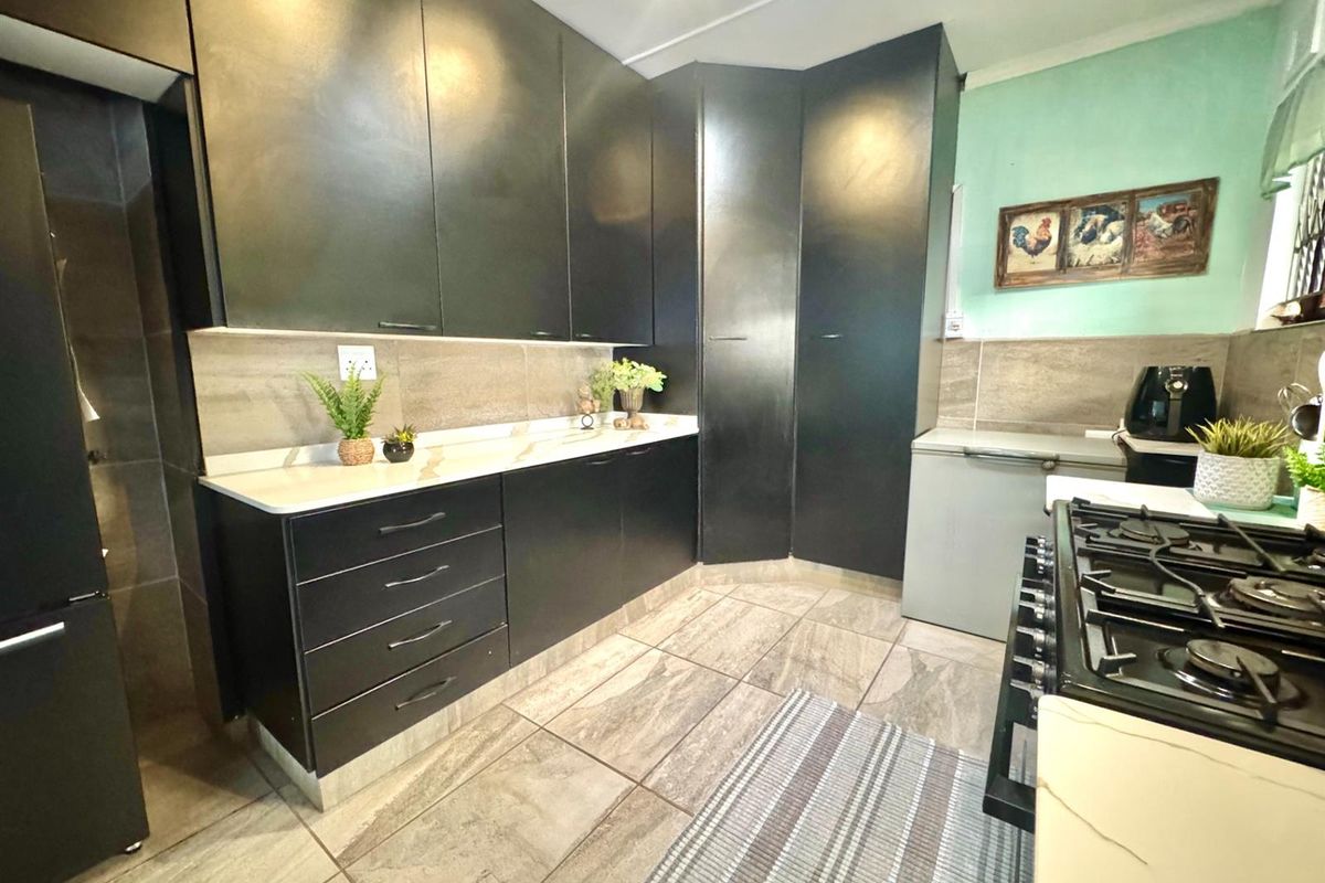 Modern kitchen featuring dark cabinetry, stone-look floor tiles, stone countertops, and a built-in gas stove with extractor.
