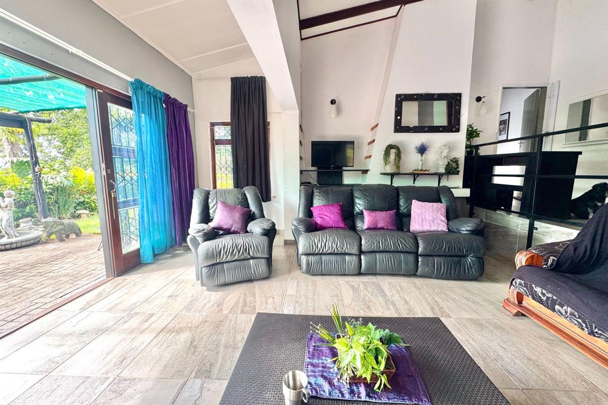 Spacious living area featuring vaulted ceilings, large sliding glass doors opening to the patio, and neutral tiled flooring.