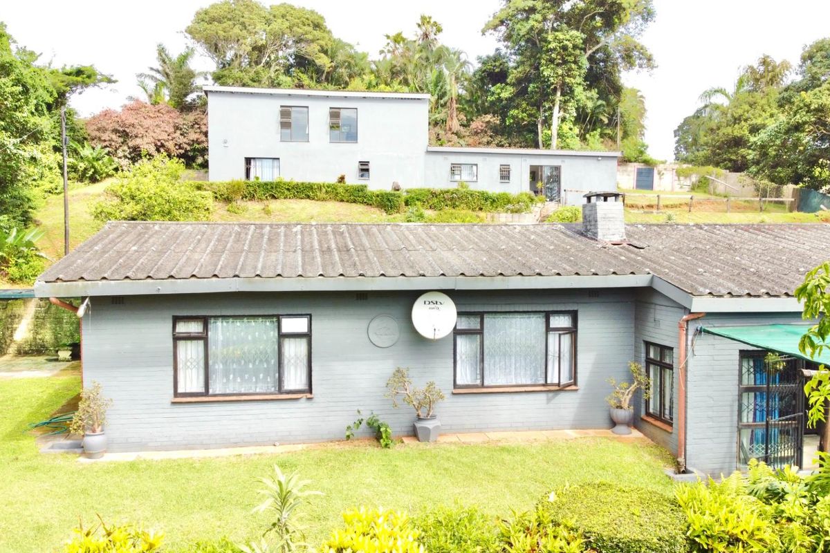 An elevated view of a single-story residential dwelling featuring a pitched roof, brick exterior, and a surrounding garden area.