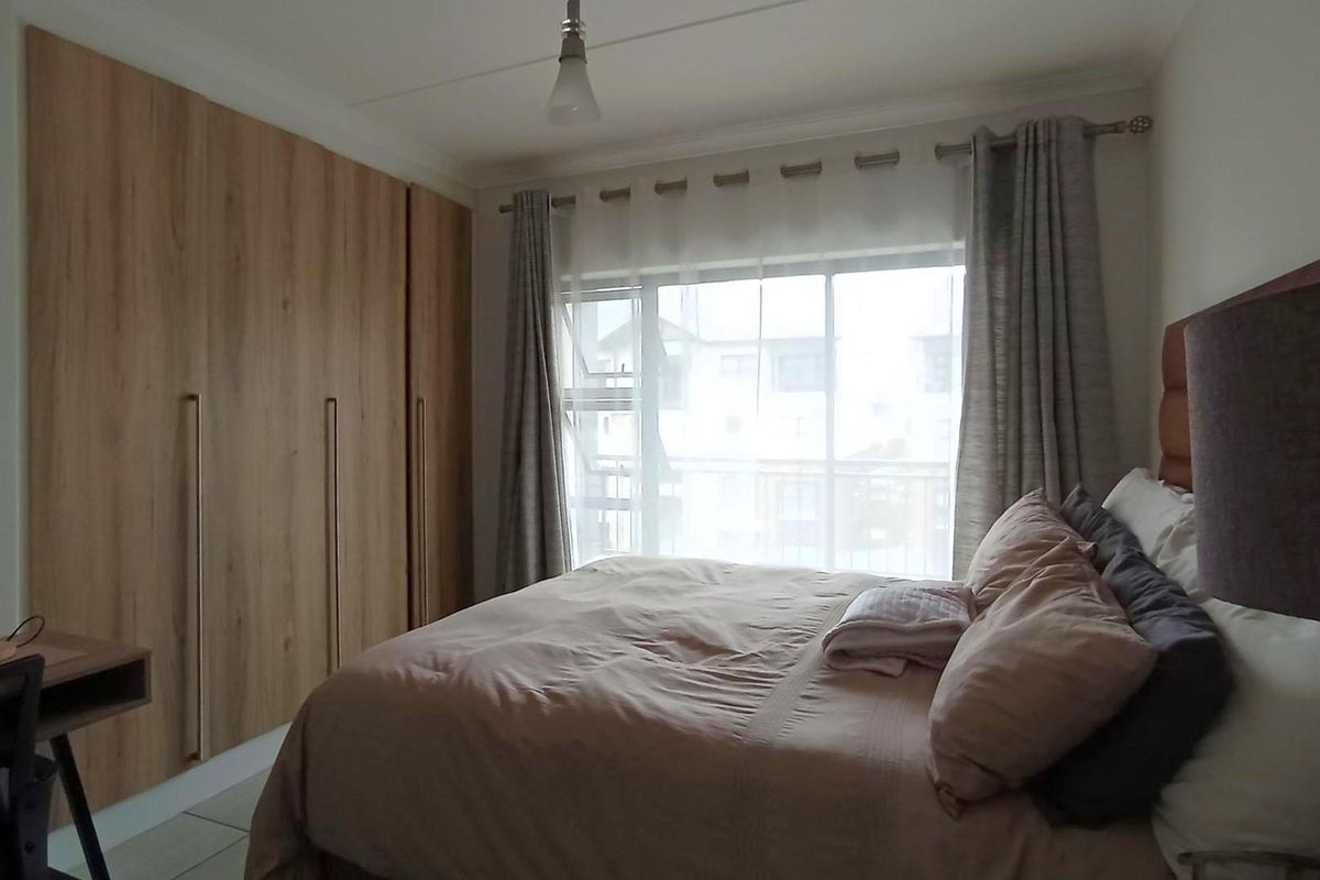 A well-maintained bedroom featuring built-in wooden cabinetry, large windows with natural light, and neutral finishes.