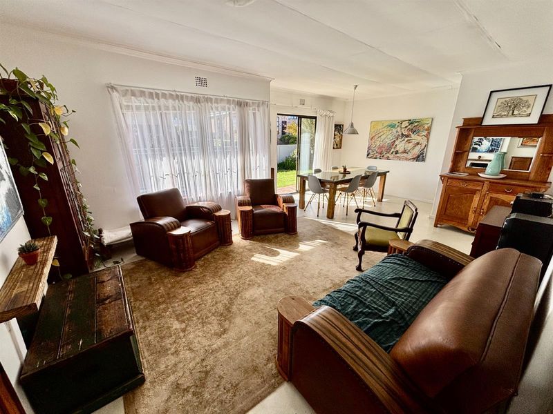 Spacious open-plan living and dining area featuring large windows and a sliding glass door providing access to the rear garden.