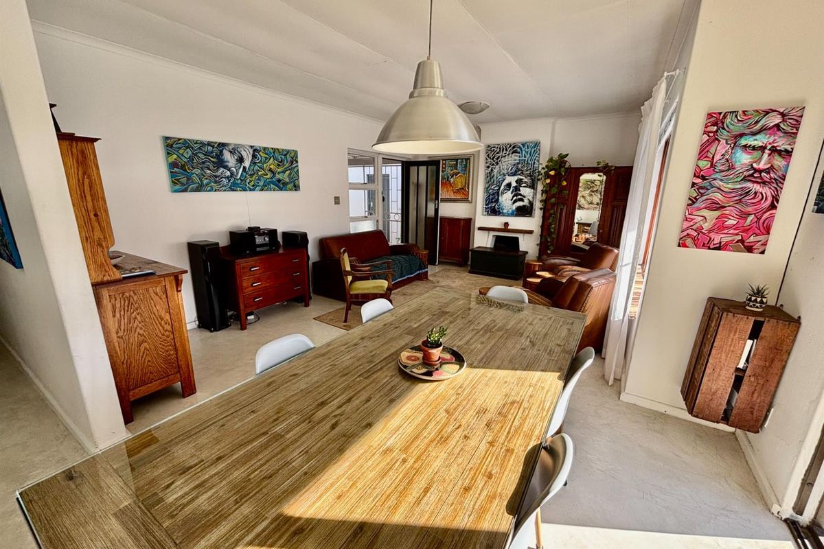 Spacious living and dining area featuring tiled flooring, coved ceilings, and a central pendant light fixture.