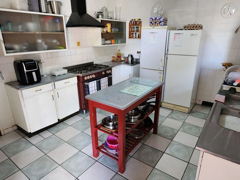 Functional kitchen featuring tiled walls and flooring, built-in cabinetry, a gas stove with extractor fan, and a double basin sink.