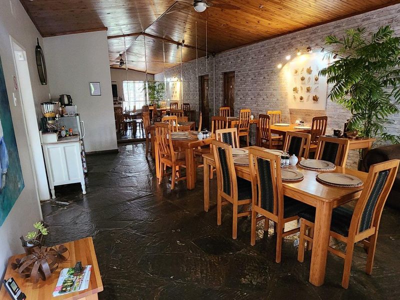 Spacious dining area featuring rustic stone flooring, a warm timber ceiling, and an exposed brick feature wall, creating a welcoming atmosphere for guests.